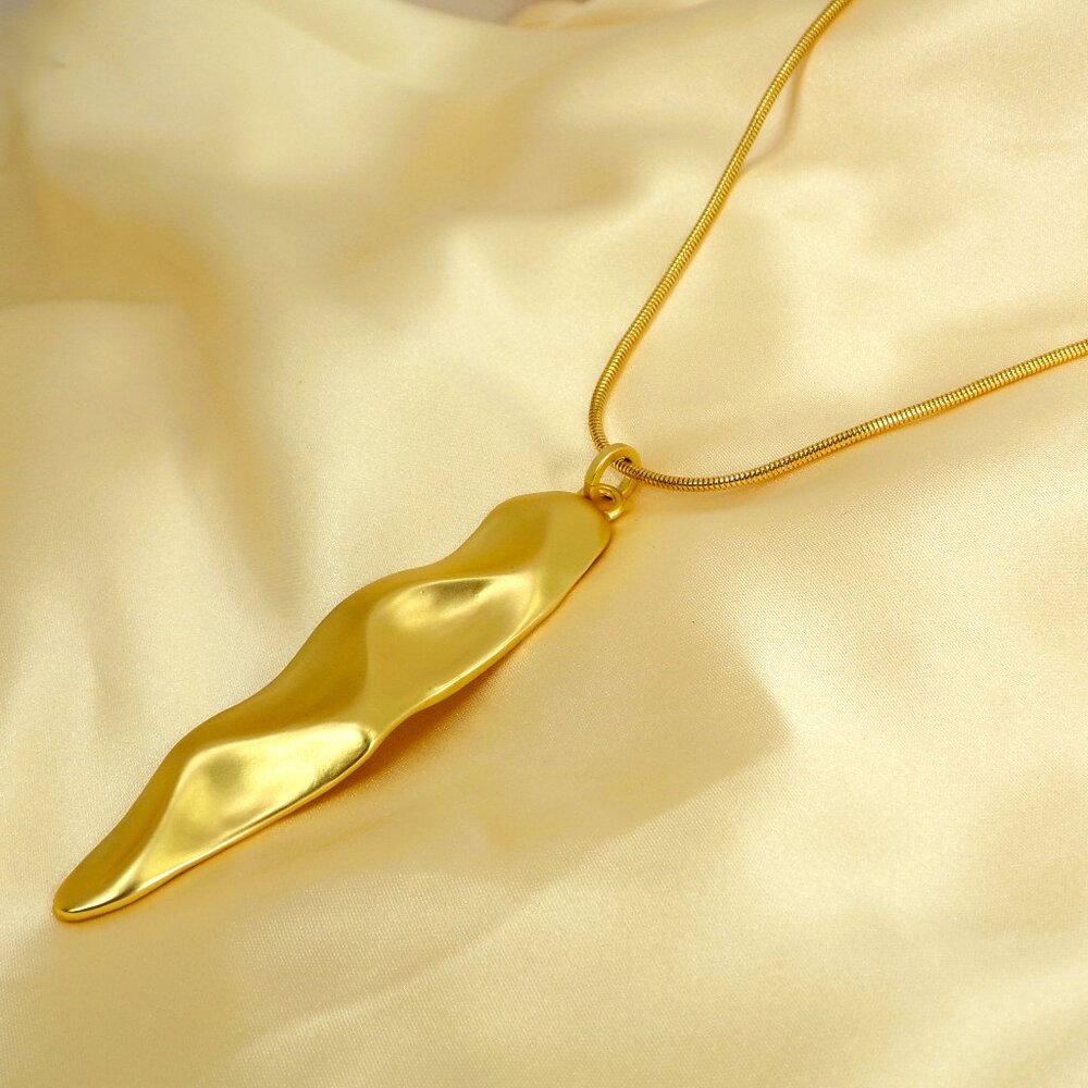 Long gold pendant necklace in a wavy cut shape and in a pretty matte gold finish